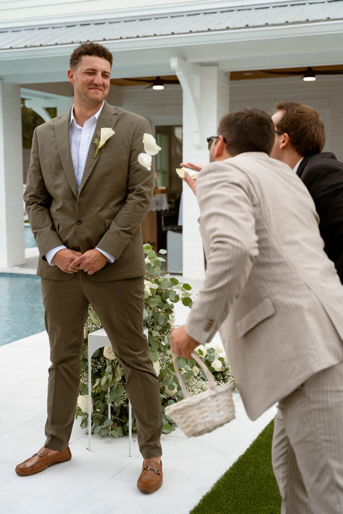 Wedding guests playfully throwing rose petals at the groom.