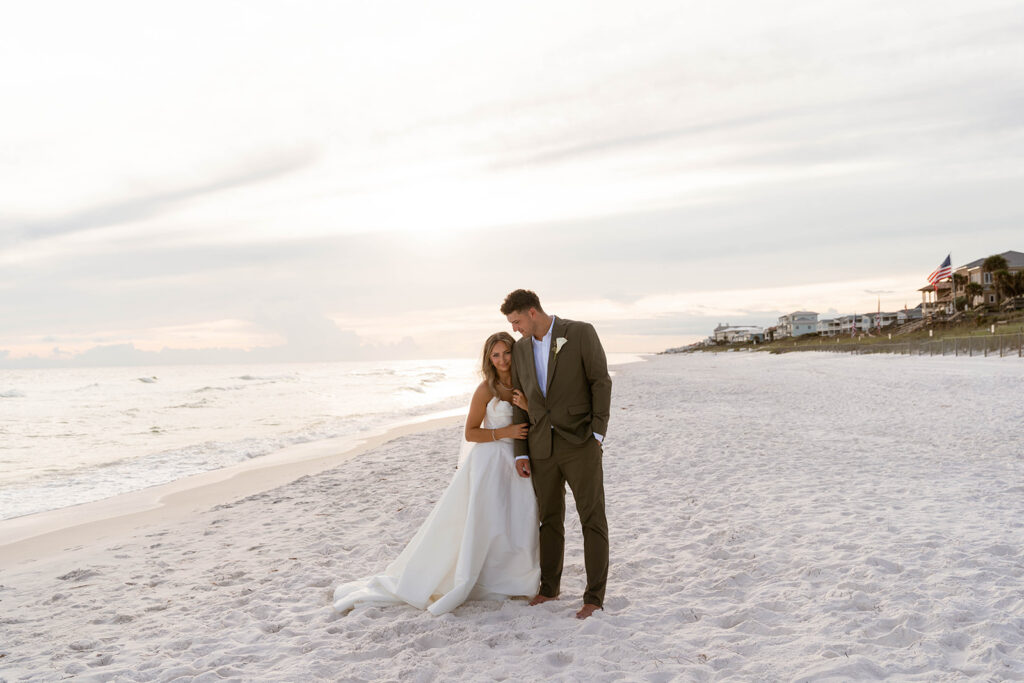 Bride and groomstanding on the beach.